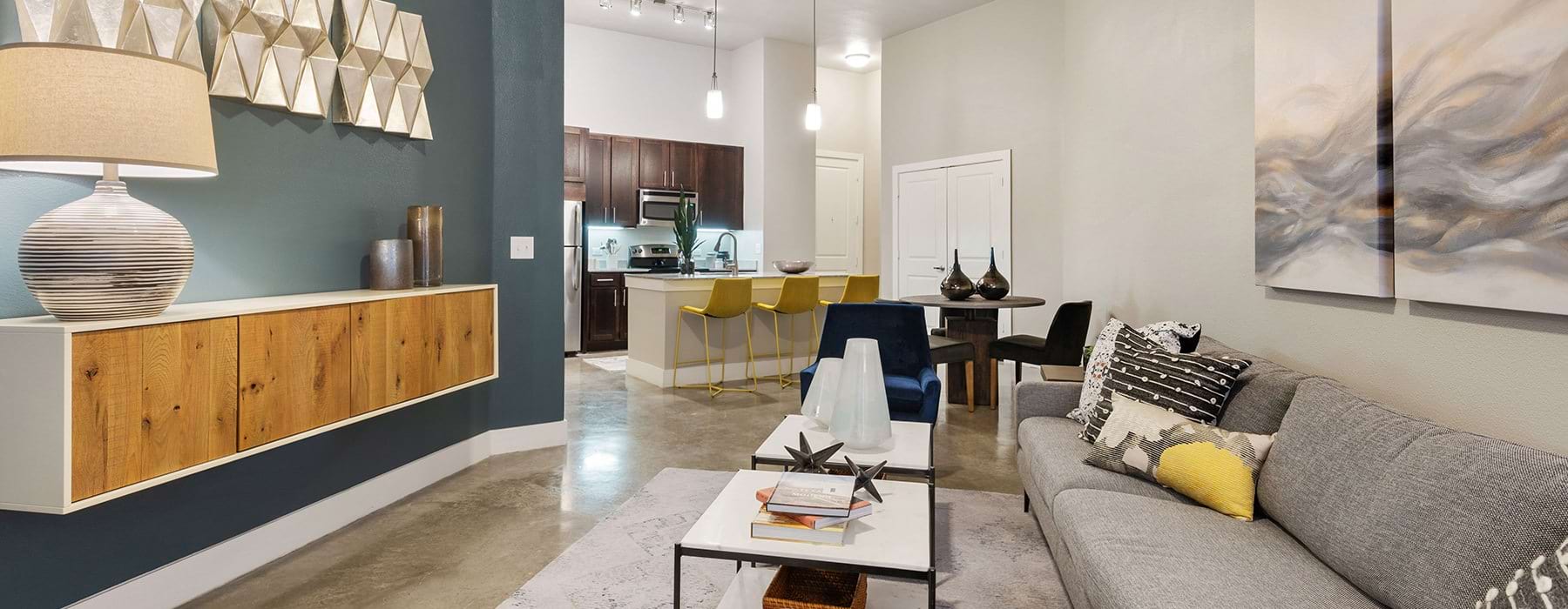 Spacious and well lit living room with wood floors and access to the kitchen 